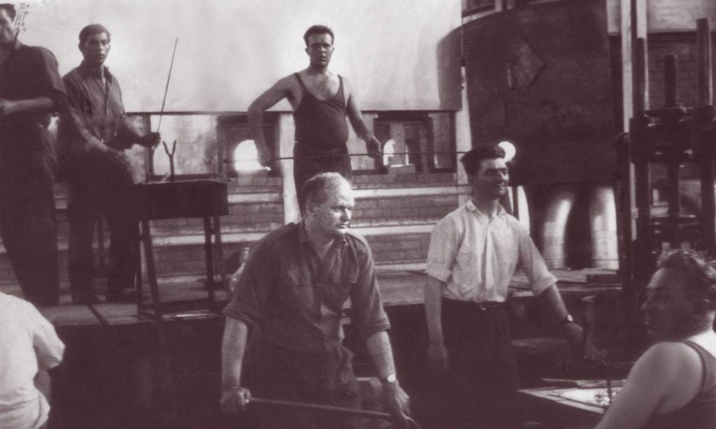 Radna atmosfera u pogonu za ručno duvano staklo, u centralnom delu slike stakloduvači Nešić Midorag i Nikola Đurić oko 1950. godine, Fond „Srpska fabrika stakla“, Zavičajni muzej Paraćin